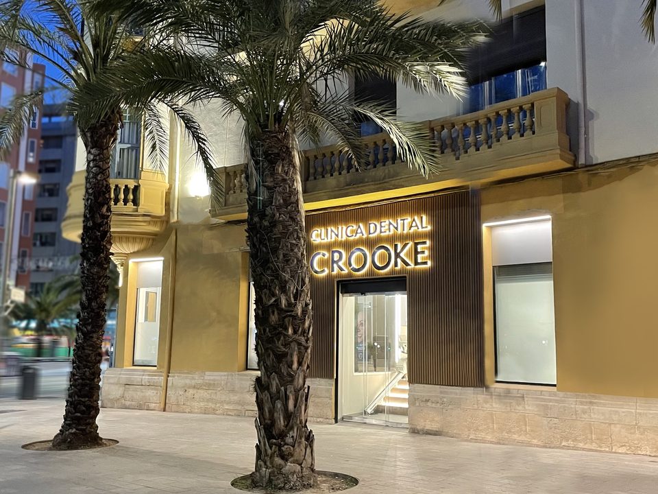 La clínica de Alicante de noche, entre las palmeras de la avenida